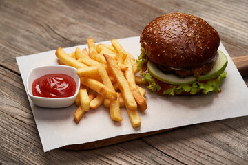 Big burger and fries on wooden table