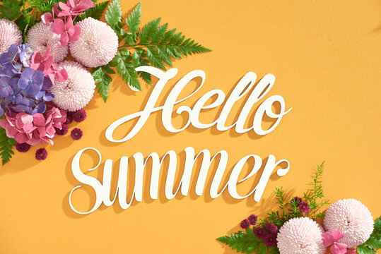 Hello summer text on yellow background with colorful background. Top view, flat lay.