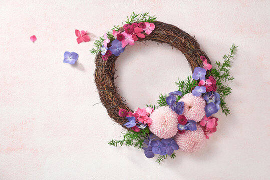Top view of floral wreath made of beautiful colorful flowers on pink background.