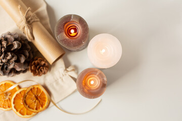 Three lighted candles, cones and orange slices are on the table. Christmas theme. View from the top point. Free space for text.