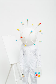 Artistic character with a big round head full of brushes working in his work.