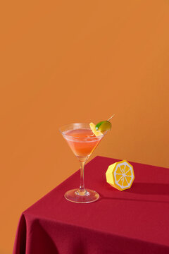 Pink cocktail with pineapple and lemon on table.