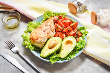 Caprese lunch bowl with grilled chicken and avocado on concrete background