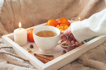 A cozy winter breakfast. A wooden tray with a cup of tea, tangerines and cinnamon. 