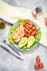 Caprese lunch bowl with grilled chicken and avocado on concrete background. Top view