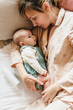 Mother and her newborn baby laying in bed.
