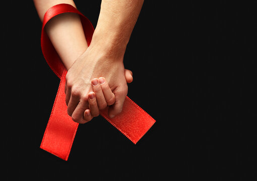 World AIDS Day. Holding hands with red ribbon.