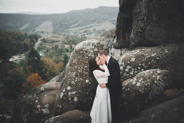 Happy wedding couple posing over beautiful landscape in the mountains