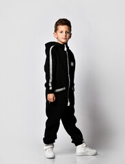 cute little boy in a black tracksuit and trousers, with the hood removed. Full-length isolated...