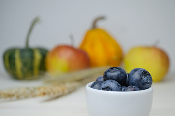 Ripe blueberries in a white Cup on a blurry background with fruit.