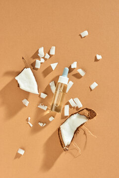Fresh coconut, bottle of oil and mint leaf on light yellow table - beautiful skincare and haircare composition