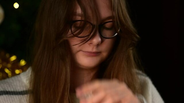 Portrait of a young girl close-up, who scratches her nose on a festive Christmas background. Winter coryza, allergy, snot, sneezing, virus, cold, slow motion