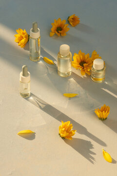 Glass bottle with aroma oil and chrysanthemum flowers on bright yellow background. Concept medicine, spa. Top view.
