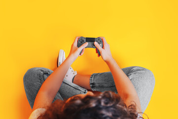 Young woman playing with gray gamepad on yellow background Color year 2021, Illuminating. © Anastassiya 