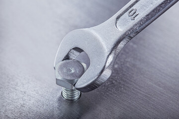 Wrench tightens bolt in steel billet. Spanner, bolt, screw and nuts.
