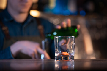 bartender preparing traditional old fashioned cocktail with whiskey and orange