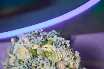 Gold rings for a wedding on a bouquet of flowers. White wedding rose bouquet . Bouquet of white roses.