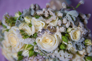 Gold rings for a wedding on a bouquet of flowers. White wedding rose bouquet . Bouquet of white roses.