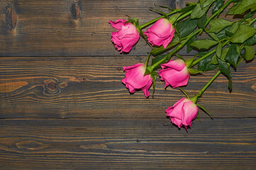 Naklejka na ściany i meble Pink roses on a wooden background, a table. View from above. The concept of a floral background.