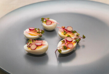 Quail eggs with micro green sprouts and radish pieces on a gray plate