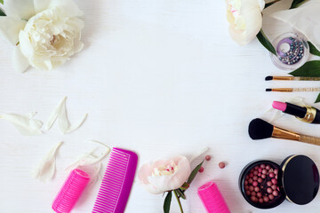 Self-care items-curlers, combs, powder, brushes, shadows - with delicate peony flowers on a light background, top view, space for text