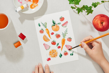 female artist painting on her project with water colours ,painting tools and brush on white desk background