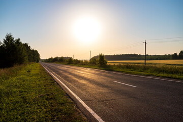 Asphalt road going through the countryside going into the distance. Summer travel concept.