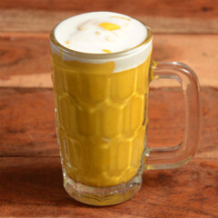 Mango Milkshake served in a glass over a rustic wooden background, selective focus on top