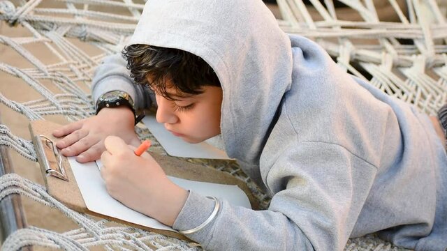 Portrait of Indian school kid drawing, sketching on page with pensile colors. Creating art at home, dreaming of becoming artist - Childhood dream, hobby concept