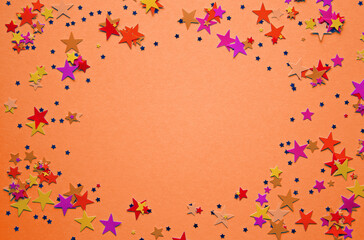 Multicolored stars confetti on peach color background. Festive confetti. Copy space. Top view. Space for text.