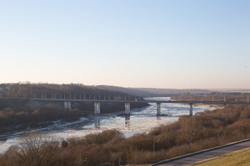 Top view of the freezing river and bridge. The river is covered with ice in winter, trees, road. Observation deck. oka, kaluga