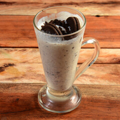 Oreo biscuit Milkshake, blended with oreo biscuits and icecream, served in a glass over a rustic wooden background, selective focus on top