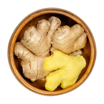 Fresh ginger roots, peeled and unpeeled, in a wooden bowl. Rhizomes of Zingiber officinale, used as a fragrant spice and as folk medicine. Close-up, from above, isolated over white, macro food photo.