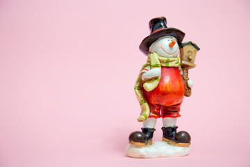 Christmas card with a place for text on which there is a snowman in a red suit and a yellow scarf and a big black hat