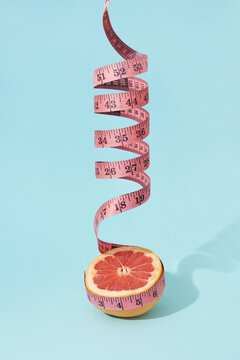 Spiral measuring tape and half of grapefruit.