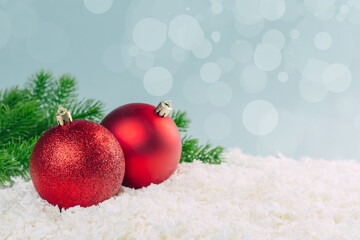 branch of a Christmas tree with Christmas balls in the snow on a blue background with bokeh lights....