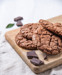 homemade chocolate cookies with chocolate chips on wood cutting board  on a light table