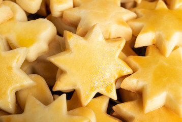 Pile of baked short bread sugar cookies in shape of stars. Traditional Swiss Christmas cookie recipe called Mailänderli. Concept for homemade Christmas presents or baking with kids. Selective focus.