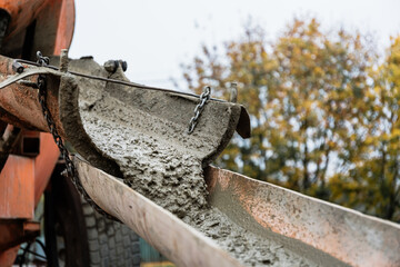 The concrete mixer unloads the concrete through a chute into a prepared container at the construction site. Building process using special equipment