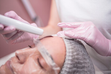 Obraz na płótnie Canvas Beautician makes facial cleansing for a girl in the salon
