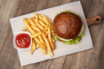 Big burger and fries on wooden table