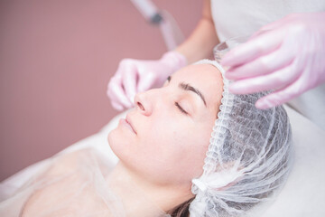 Fototapeta na wymiar Beautician makes facial cleansing for a girl in the salon