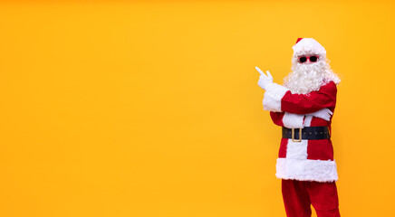 Weihnachtsmann vor gelben Hintergrund zeigt mit dem Finger nach links oben
