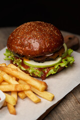 Big burger and fries on wooden table