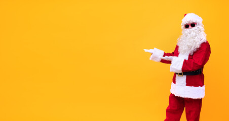 Weihnachtsmann vor gelben Hintergrund präsentiert mit beiden Händen