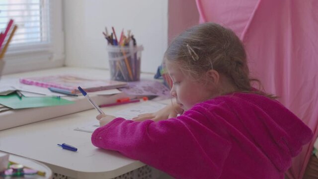 little girl learning to write, distance learning for children in quarantine, focused child doing a task in writing
