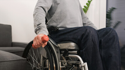 Fototapeta premium Man in wheelchair exercising and lifting weight in a living room.