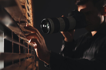 Fototapeta Private detective with camera spying near window indoors obraz