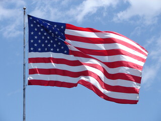 American Flag of the United States Of America, waving in the breeze with blue sky behind