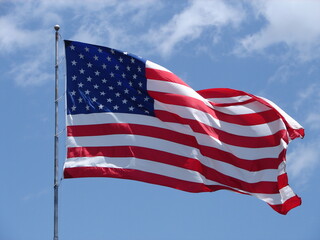 American Flag, stars and stripes, blowing in the wind with a blue sky behind